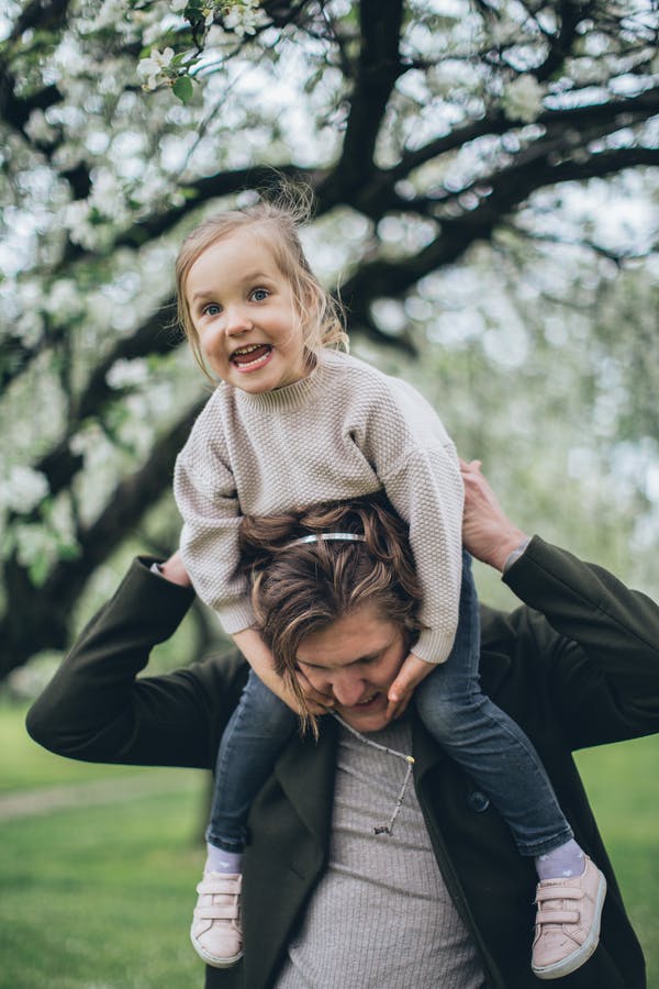 Young girl delighted to be sitting on an adults shoulders