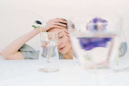 Person holding head in hands as seen through glass of water