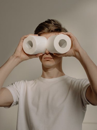 older boy holding toilet rolls up to his eyes as though they are binoculars