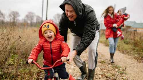Child on balance bike with man, woman holding baby
