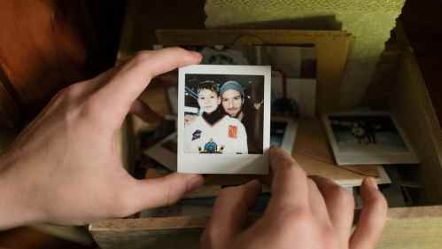 hands holding old polaroid photograph of a man and boy