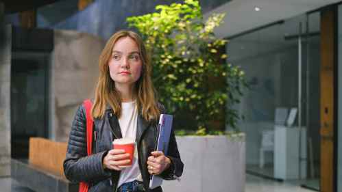 Young woman carrying laptop and coffee
