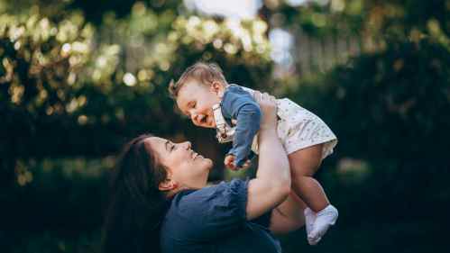 woman holding smiling baby in the air